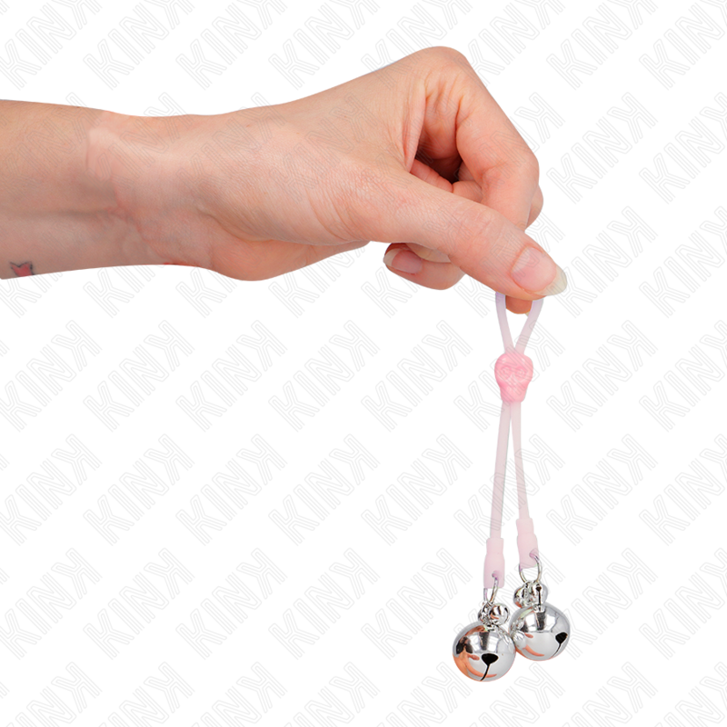 Pince a tetons en silicone rose a billes metalliques tenue entre les doigts, mise en valeur du serrage par noeud coulissant et du lest, accessoire Kink.