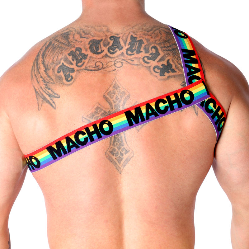 Harnais homme Macho à sangle arc-en-ciel et rouge porté de face sur torse nu musclé tatoué, soulignant un style fétichiste coloré et un maintien diagonal structurant près du corps.