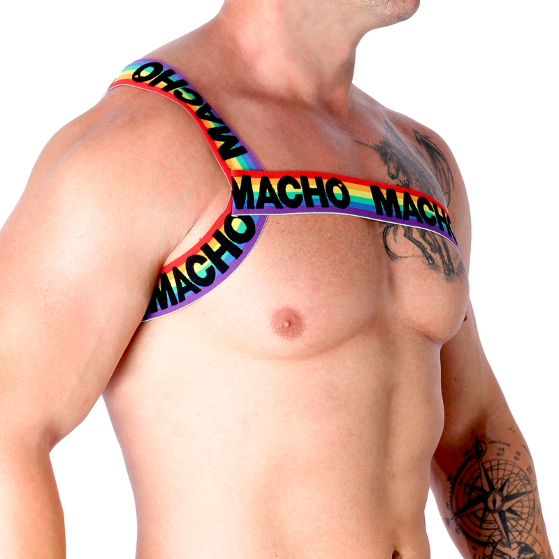 Harnais homme Macho arc-en-ciel vu de face sur torse nu musclé, sangle colorée diagonale sur la poitrine, illustrant la coupe ajustée et le look fétichiste affirmé près du corps.
