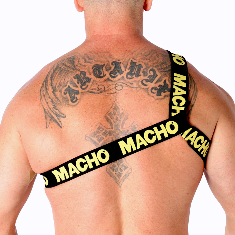 Harnais homme Macho à sangles jaunes vu de dos sur dos très tatoué musclé, bandes logo croisées entre les omoplates, affirmant un look fétichiste structurant près du corps.