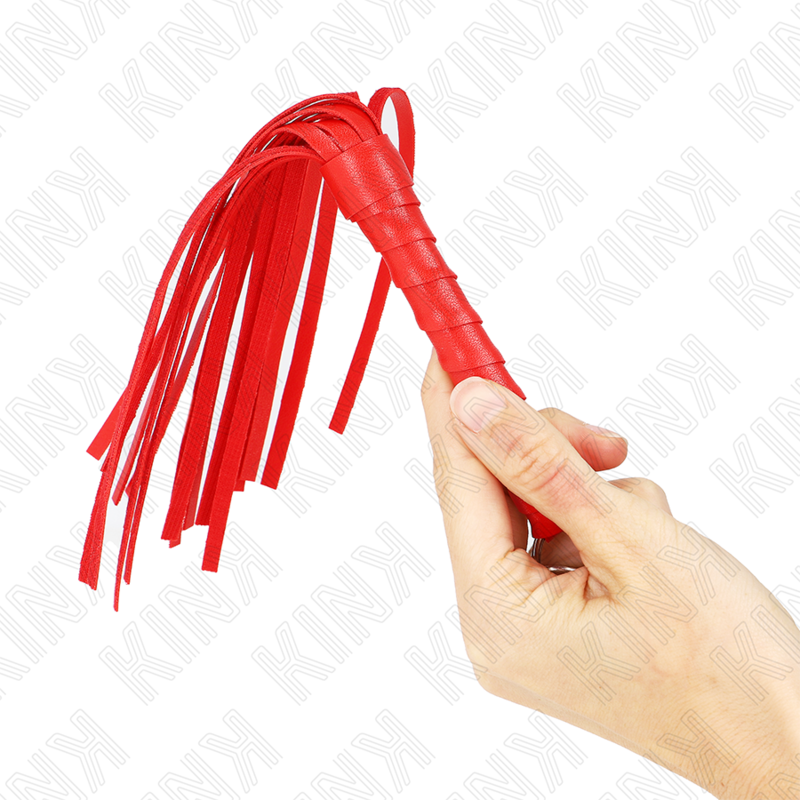 Mini martinet rouge tenu entre les doigts, fines lanieres etalees en eventail. Accessoire de discipline soft compact pour des tapes legeres et sensorielles.