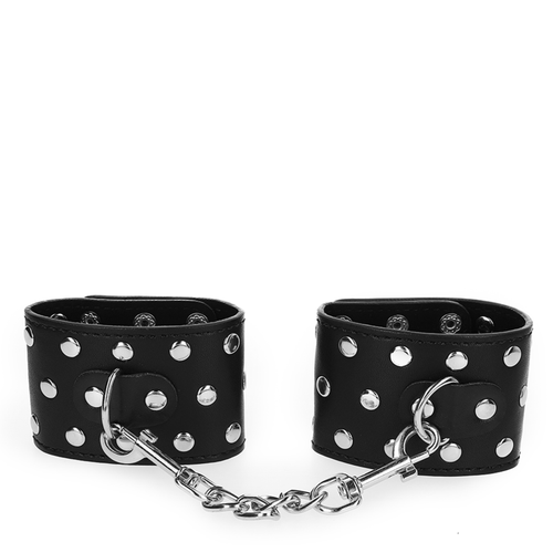 Paire de manchettes de poignets noires a rivets reliees par une chaine argentee, vue d'ensemble des attaches a pression du kit de contention