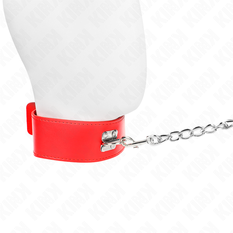 Collier de soumission rouge en cuirette fermé autour du cou d'un mannequin, chaîne de laisse partant sur le côté, accessoire de domination BDSM ajustable.