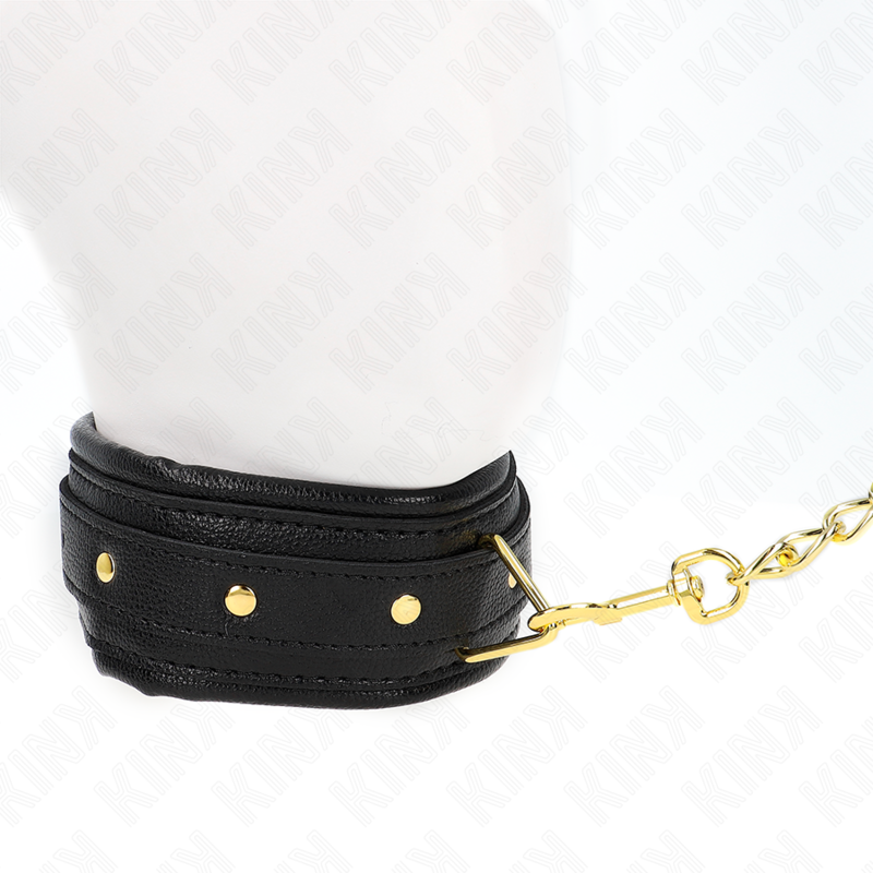 Collier de soumission en cuir noir a rivets dores porte sur un buste mannequin blanc, chaine doree attachee a l'anneau, accessoire de contention du cou.