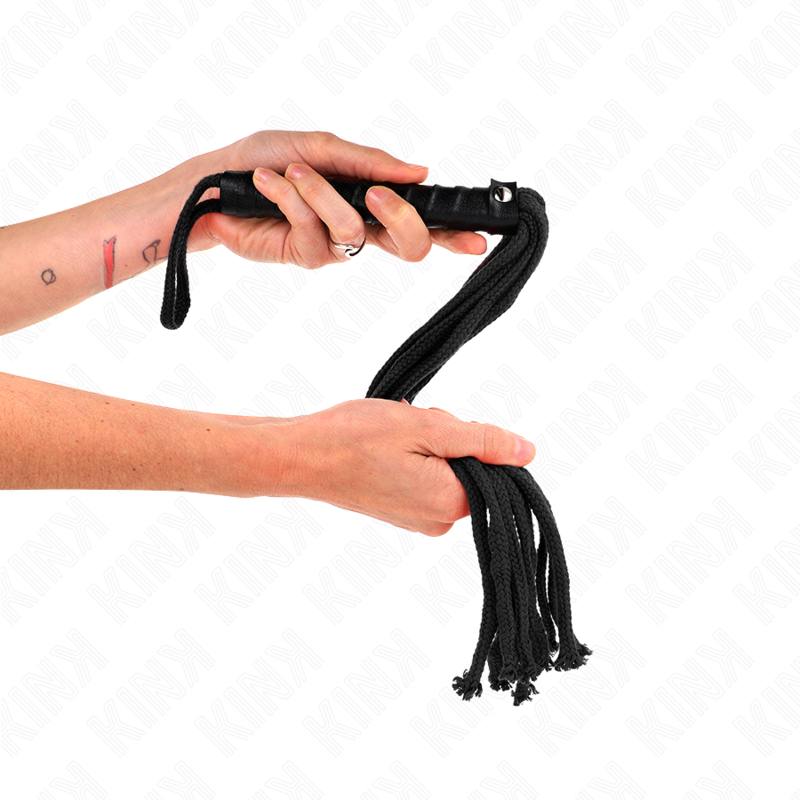 Manche tressé du martinet en corde noire tenu en main, gros plan sur la poignée et la boucle de suspension de l'accessoire de discipline.