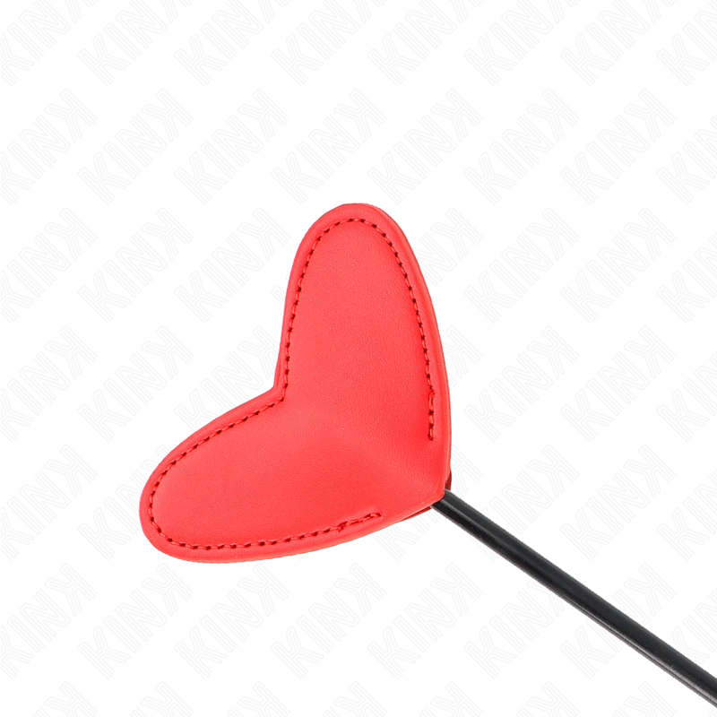 Gros plan sur la palette cœur rouge en simili-cuir surpiquée de la tapette de fessée, détail des coutures, accessoire de spanking au design tendre et marqué.