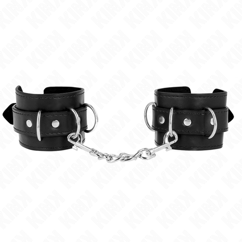 Paire de manchettes de poignets en cuir noir a anneaux en D, reliees par une chaine argentee torsadee, posees a plat sur fond blanc, accessoire de bondage.