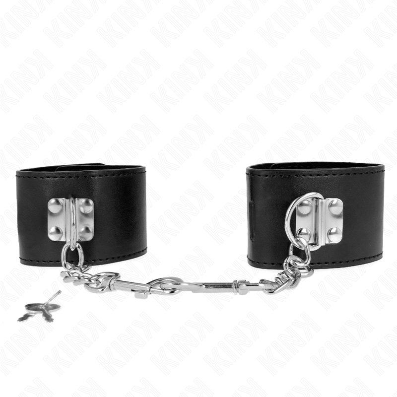 Paire de larges menottes de poignets en cuir noir a fermoir levier reliees par une chaine, avec cles, fond blanc : contention robuste pour le jeu de domination.