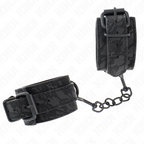 Gros plan de menottes de poignets en cuir noir gaufre dentelle a boucle et chaine noires : contention raffinee tout en noir pour les jeux de soumission a deux.