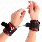 Manchettes de poignets en neoprene noir a dentelle rouge portees aux poignets et reliees par chaine, contention BDSM douce au look sensuel.