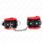Paire de manchettes de poignets noires a doublure rouge et anneaux en O reliees par chaine, posees sur fond blanc, accessoire de contention sensuel.