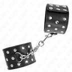 Manchette de poignet en cuir noir a rivets argentes et mousqueton sur chaine, vue rapprochee de la finition cloutee de cet accessoire de contention.