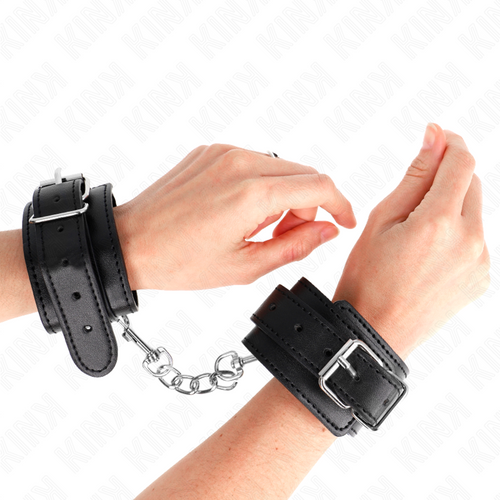 Poignets entravés par des menottes en cuir noir à boucle reliées par une chaîne métallique, kit d'attache de bondage au look fétiche pour la soumission