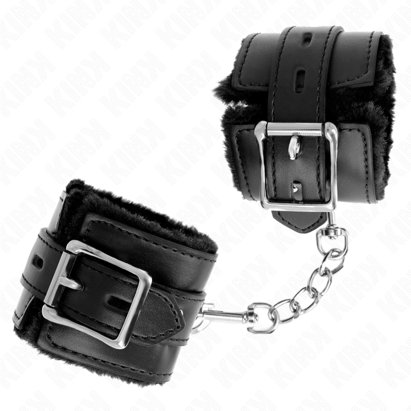 Manchette de poignet en cuir noir a doublure fourrure, gros plan sur la boucle argentee et la chaine, accessoire de contention soft pour jeux de soumission.