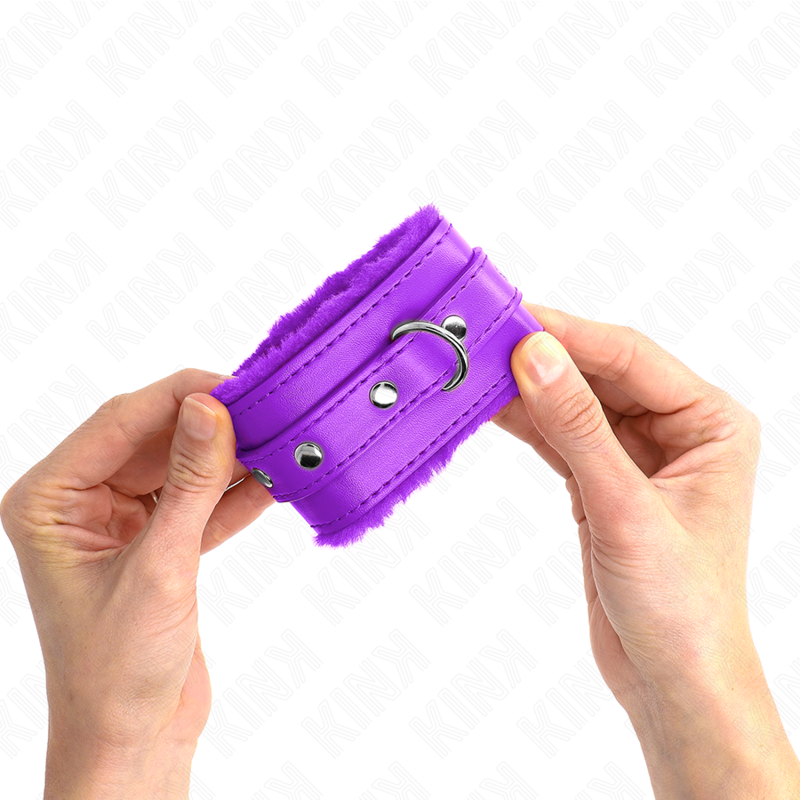 Menotte de poignet violette doublee de fourrure tenue des deux mains, anneau en D visible : contention moelleuse et feminine pour les jeux de soumission.