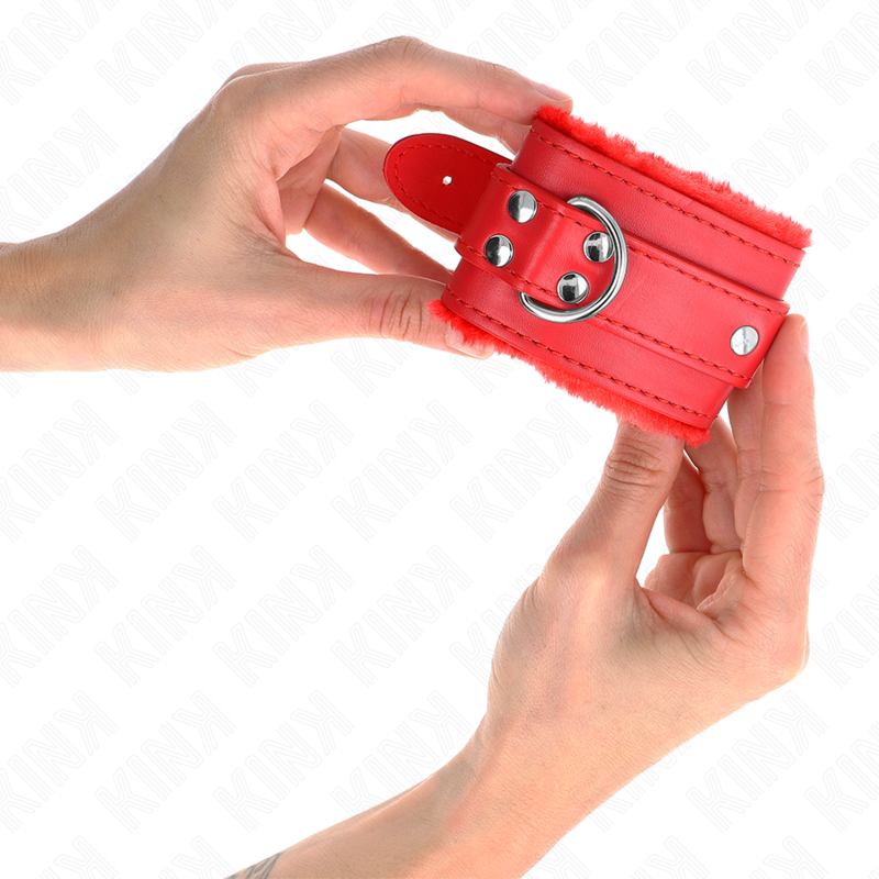 Gros plan d'une manchette rouge a anneau metallique doublee de fourrure tenue en main, point d'attache du kit de contention confortable