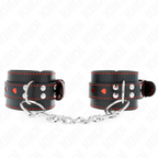 Paire de manchettes de poignets noires ornees de coeurs rouges et surpiqures, reliees par chaine, posees a plat sur fond blanc, contention BDSM glamour.