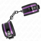 Manchettes de poignets violet et noir a boutons-pression et chaine noire, vue rapprochee du contraste bicolore de cet accessoire de contention BDSM.