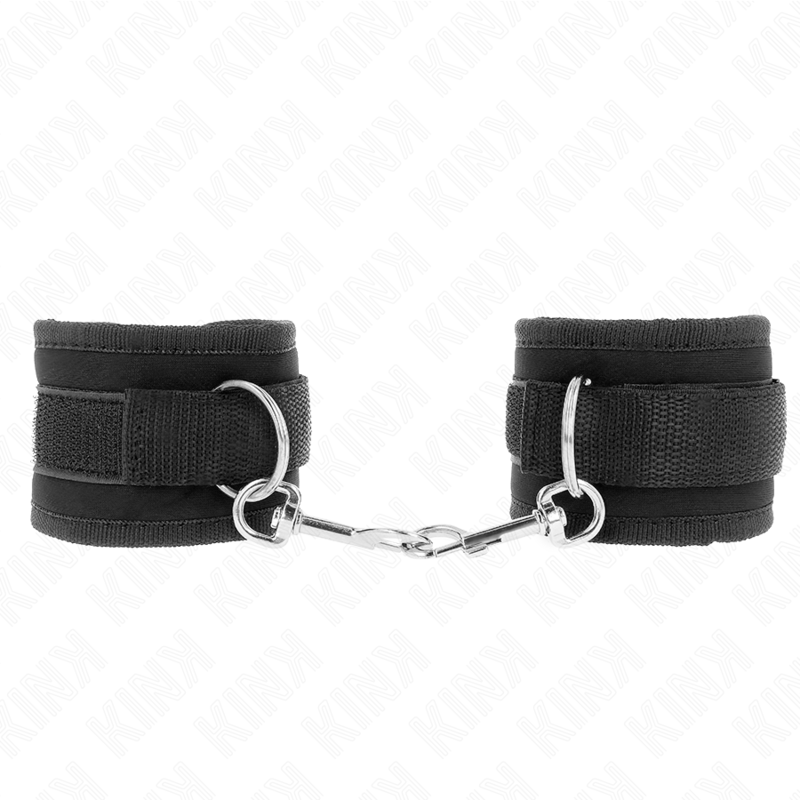 Paire de manchettes en nylon noir matelassé reliées par une chaîne et mousqueton, vue à plat sur fond blanc, attache-poignets sobre pour jeux de bondage.
