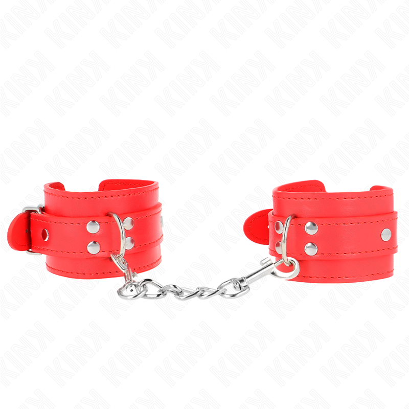 Paire de menottes en cuir rouge à rivets reliées par une chaîne métallique, posées à plat, kit d'attache de contention au style affirmé et sensuel