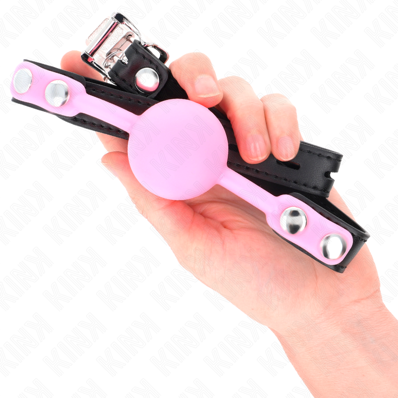 Baillon boule rose en silicone tenu en main pour montrer l'echelle, sangle reglable a boucle, accessoire BDSM de domination tout en douceur.