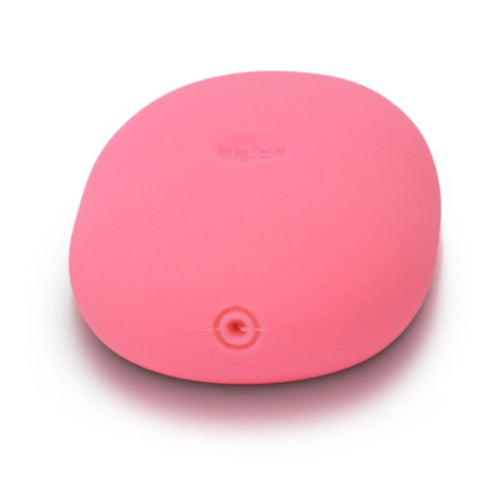 Galet vibrant clitoridien rose vu de trois quarts, surface lisse bombée avec un bouton de commande central rond, finition mate du produit détaillée de près sur fond blanc épuré.