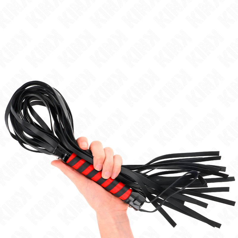 Martinet en cuir noir au manche rouge tenu en main, lanieres retombantes. Fouet de discipline maniable pour doser l'intensite, de l'effleurement au claquement plus appuye.