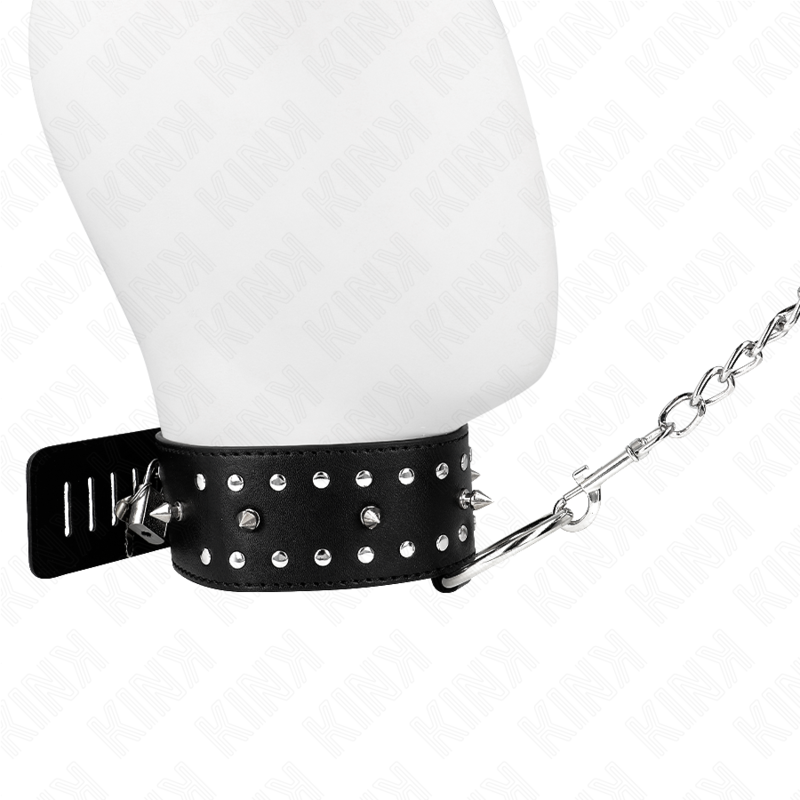 Gros plan du collier de soumission noir clouté sur buste mannequin, chaîne argentée tendue de côté. Accessoire BDSM rock au maintien marqué.
