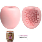 Masturbateur oeuf rose ferme et en coupe devoilant la texture interne nervuree en TPR, etui tonneau Sauternes pour un rangement discret.