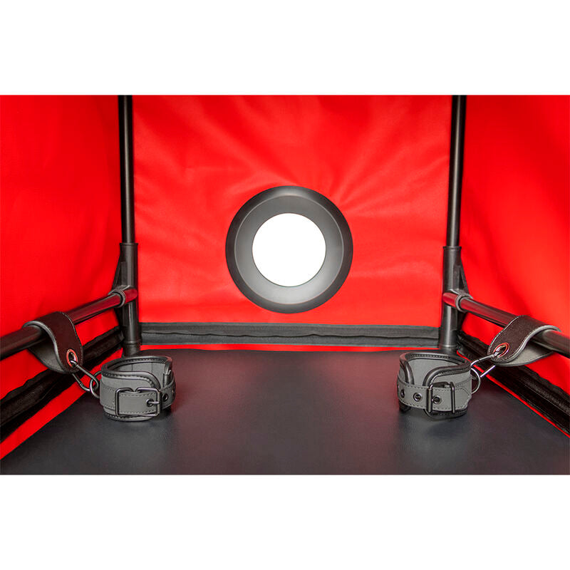 Interieur rouge de la cabine Secret Dome montrant un orifice circulaire cercle de gris et deux menottes de maintien attachees a l'armature noire