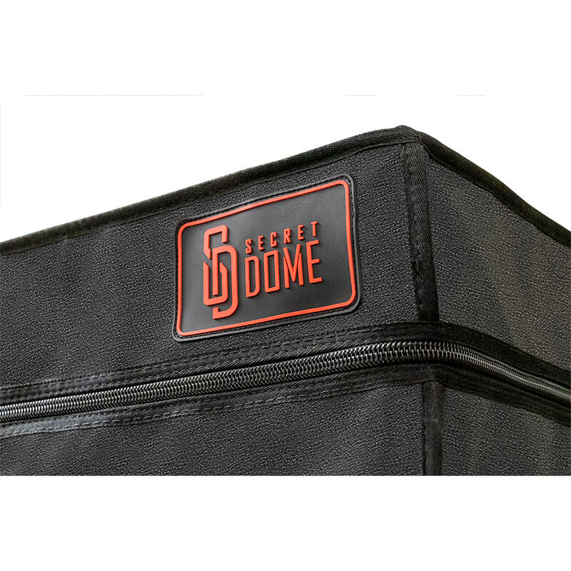 Gros plan sur le logo Secret Dome brode et la fermeture eclair d'angle de la cabine, tissu noir matelasse et coutures contrastees nettes