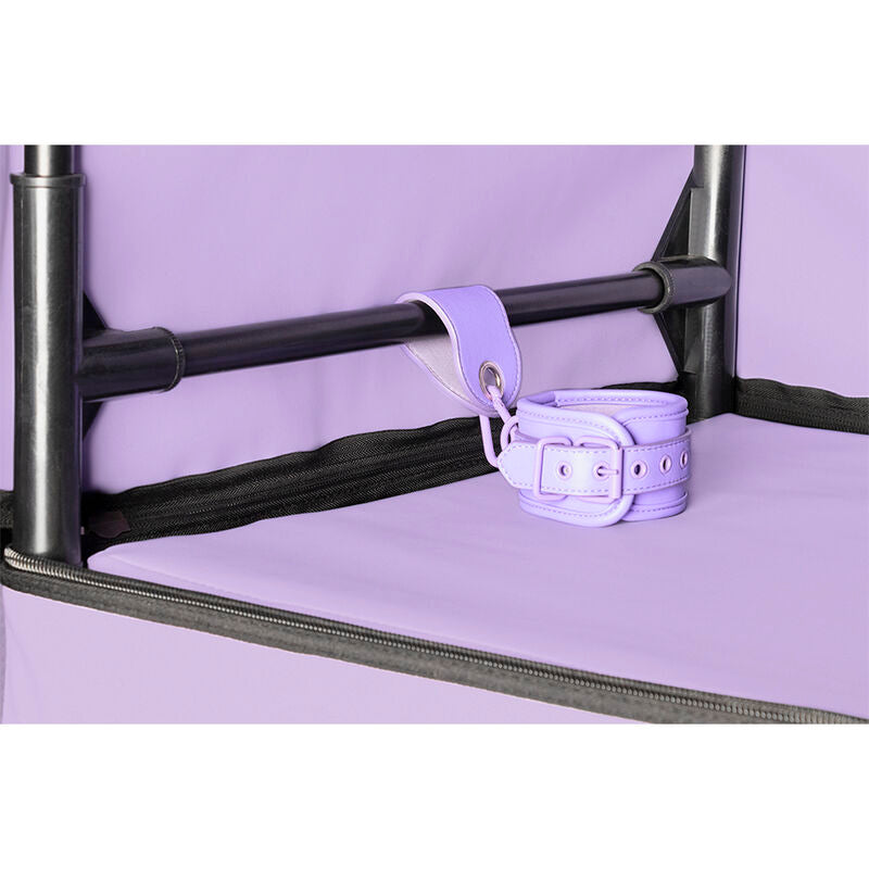 Detail d'une menotte de maintien lilas fixee a l'armature tubulaire noire de la cabine Secret Dome, sur fond de doublure interieure violet pastel