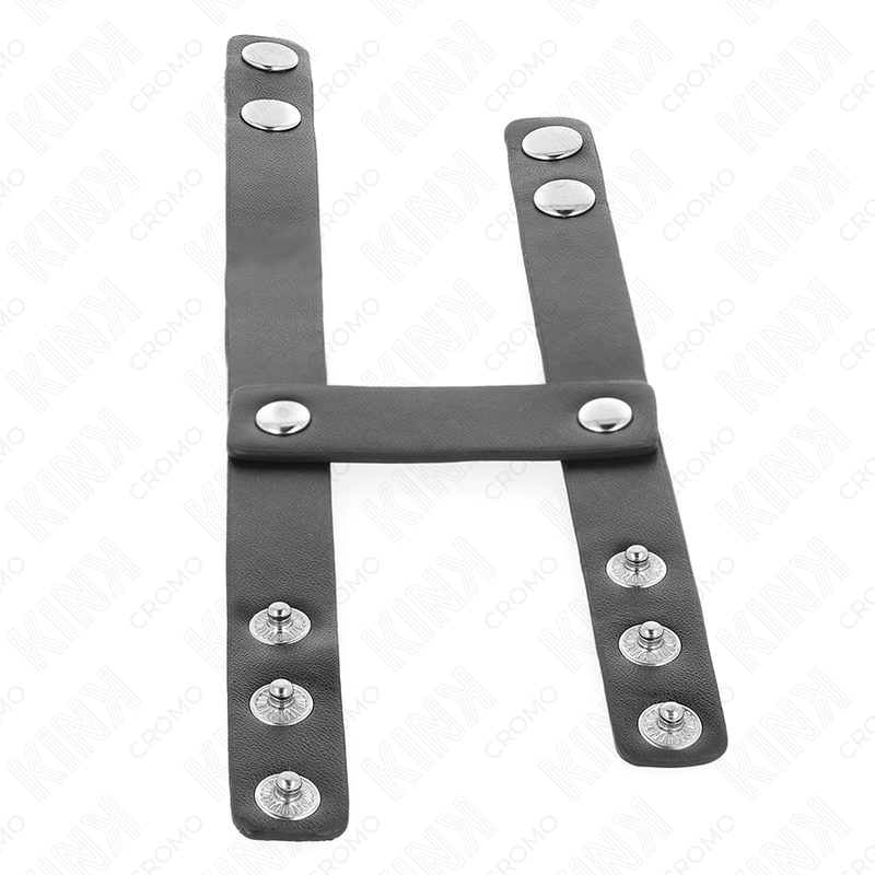Harnais cuir noir en forme de H a rivets, accessoire de contention penienne BDSM masculin presente debout sur fond blanc