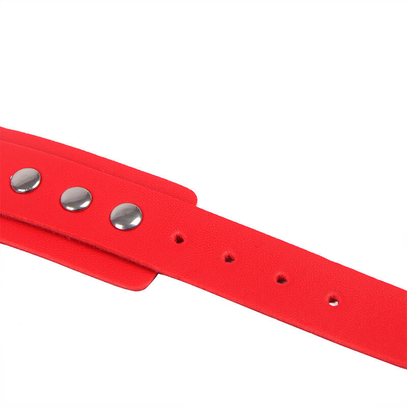 Gros plan sur une sangle en cuir rouge perforee du harnais Subblime, rivets argentes alignes et trous de reglage visibles sur fond blanc.