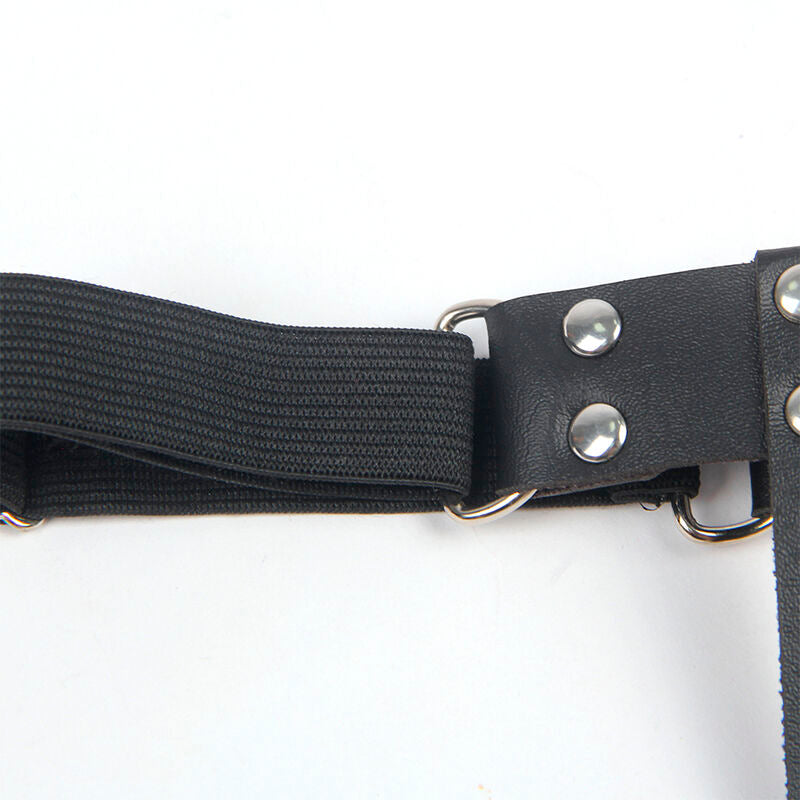 Gros plan de la sangle elastique noire et des boutons pression du harnais de jambe Subblime, finition reglable, accessoire fetichiste pose a plat.