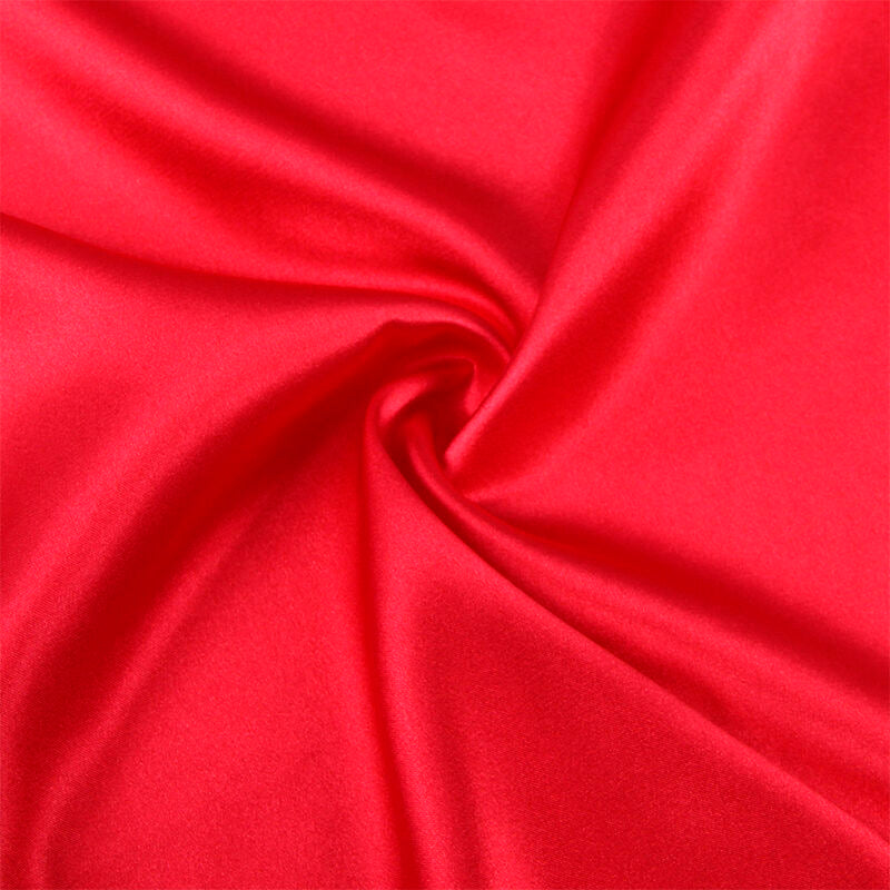 Gros plan sur le satin rouge brillant du peignoir Subblime, drape lumineux et plis fluides, detail de texture soyeuse haut de gamme.