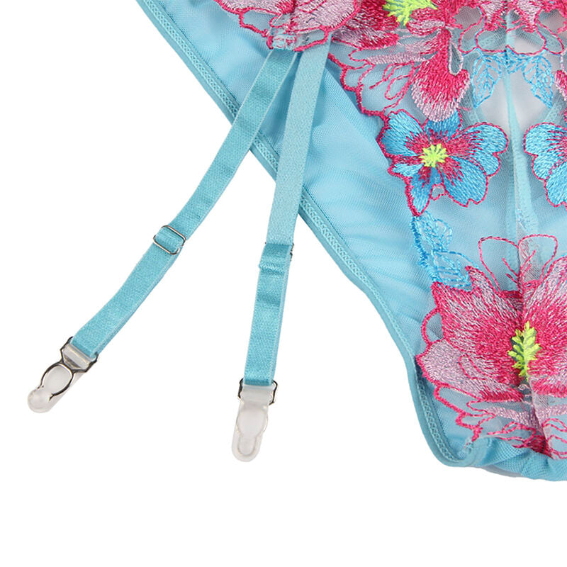 Gros plan a plat du porte-jarretelles turquoise Subblime a broderie florale rose vif et pinces metalliques, maille fleurie et sangles ajustables etalees sur un fond blanc neutre.