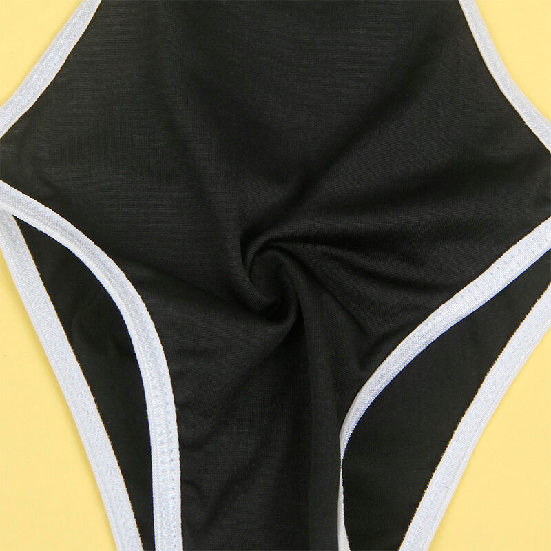 Gros plan a plat de la culotte noire du costume soubrette Subblime a bords blancs contrastes et decoupe arriere echancree, posee sur un fond jaune uni.