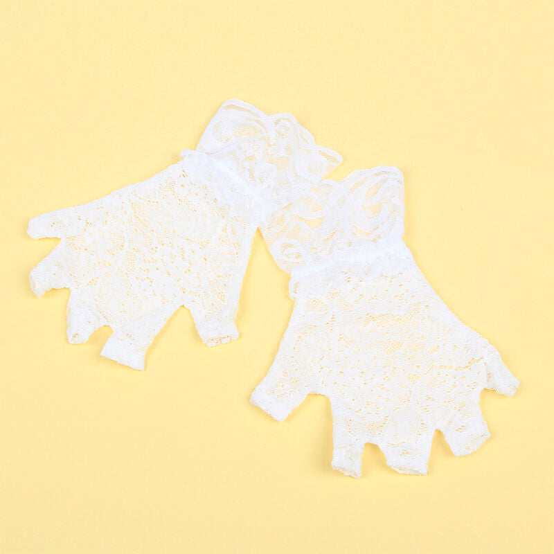 Gros plan a plat de la paire de gants en dentelle blanche du costume soubrette Subblime, finition a volants posee seule sur un fond jaune uni lumineux.