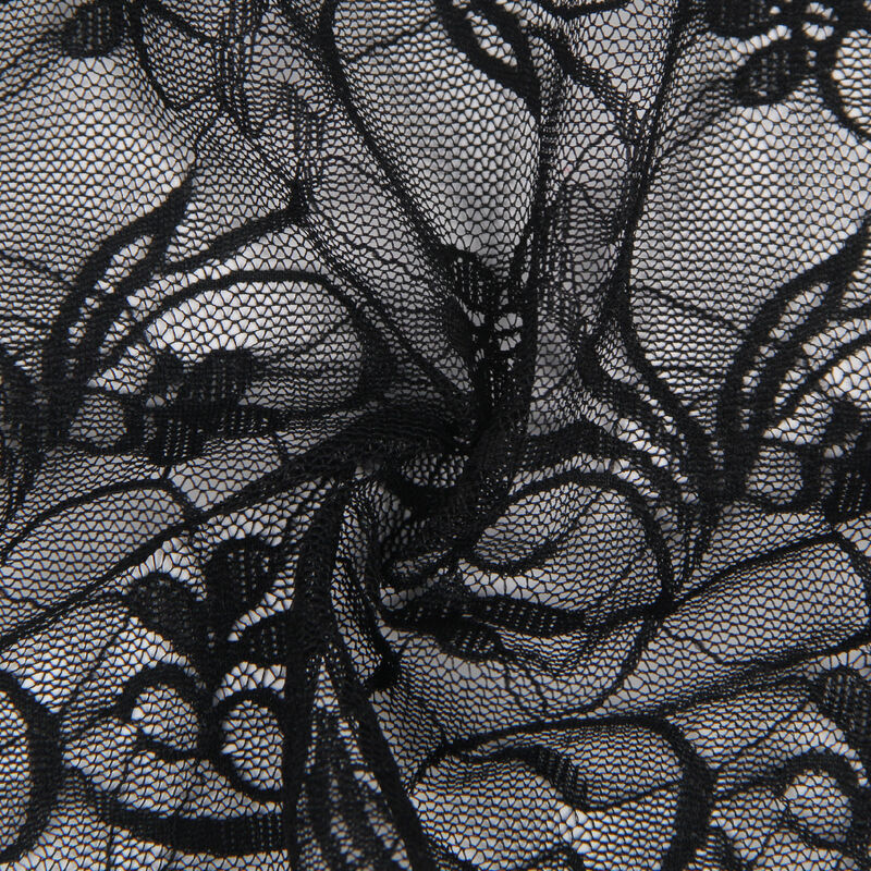Macro de la dentelle florale noire Subblime, maille fine extensible aux motifs de fleurs ajourees, texture transparente typique de cette nuisette sensuelle.