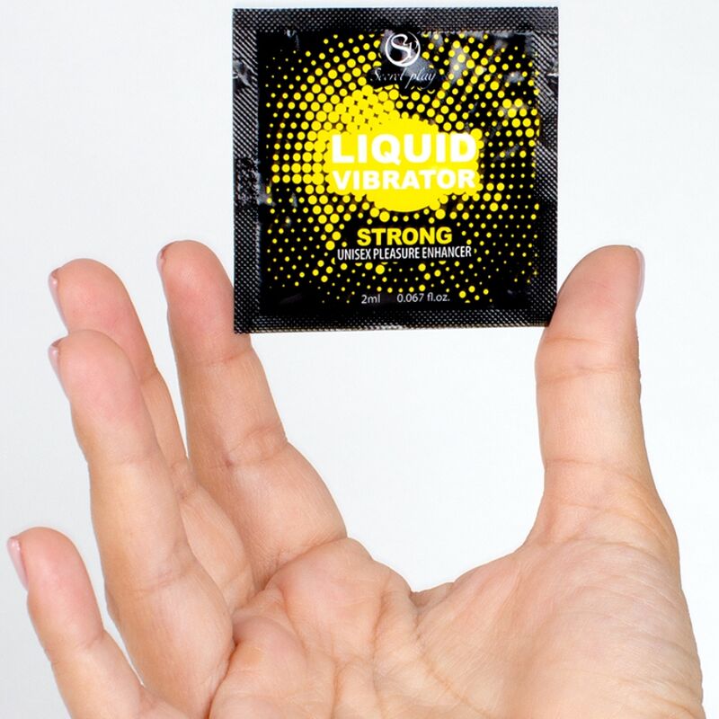 Sachet unidose Liquid Vibrator Strong tenu dans une main, dosette jaune Secret Play effet vibrant unisexe, gros plan montrant le format echantillon 2 ml du gel stimulant.