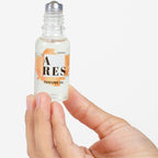 Flacon roll-on a bille Ares For Men aux pheromones tenu entre les doigts, huile de parfum masculine 20 ml Secret Play a appliquer sur les zones de pulsation.