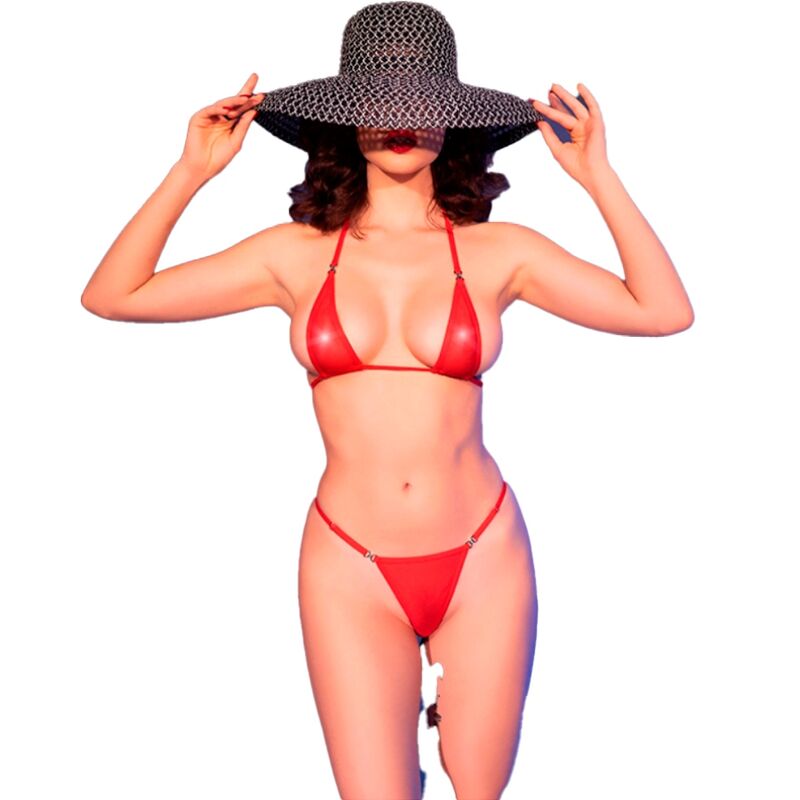 Modèle ajustant son chapeau en micro-bikini rouge brillant Chilirose. Bustier minimaliste et string fin sur fond bleu, allure pin-up.