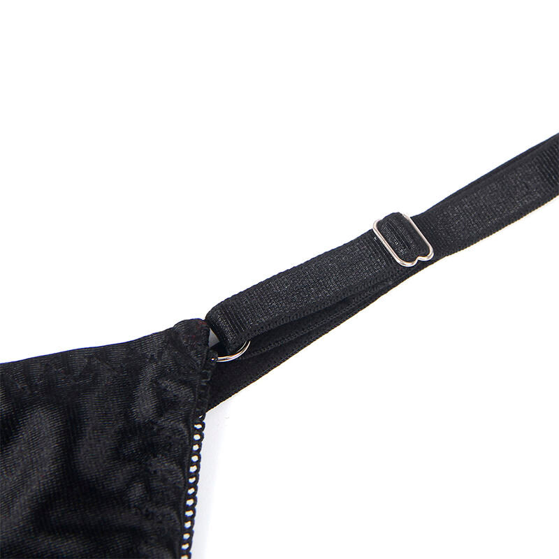 Gros plan sur le satin noir froisse et la finition strass de l'ensemble Subblime a noeud, detail textile en macrophotographie sur fond blanc.