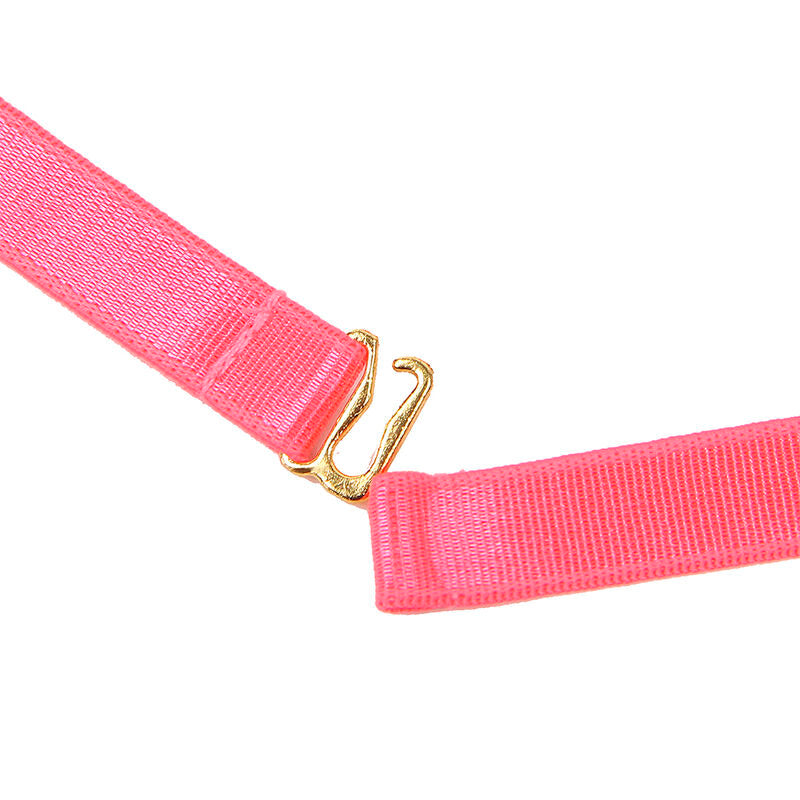 Macro sur une sangle rose fluo et son crochet dore, texture de l'elastique et fixation metallique de la jarretiere Subblime sur fond clair.