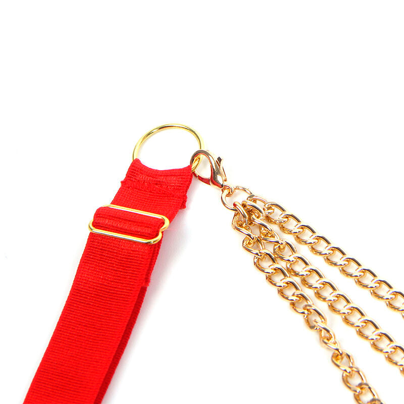 Gros plan sur l'anneau dore et les chaines pendantes de l'ensemble rouge Subblime, detail bijou de corps sur fond blanc.