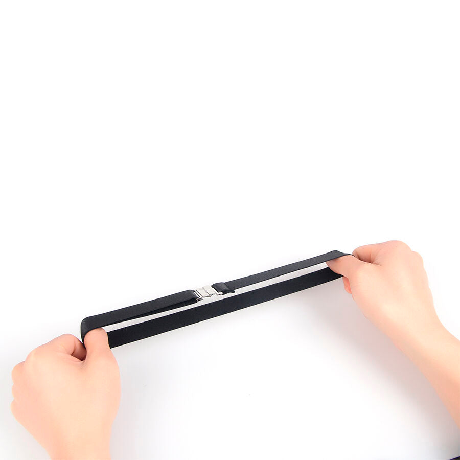 Anneau de jambe en simili cuir noir Subblime tenu et etire entre deux mains : sangle elastique a boucle metal, demonstration de l'extensibilite de l'accessoire.