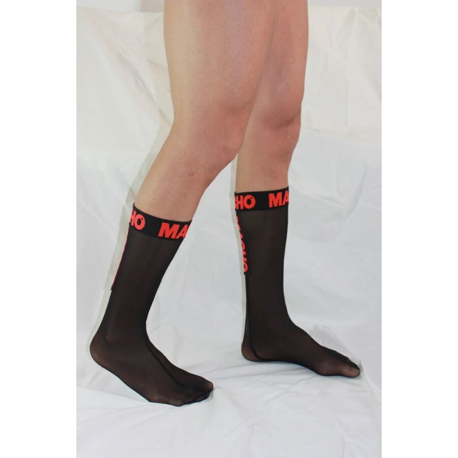 Chaussette haute homme noire semi-transparente portee de profil, bord logo Macho rouge, maille fine fetichiste epousant le mollet et la cheville.