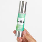 Flacon airless de lotion corporelle Gaia For Women Silk Skin tenu en main, soin hydratant soyeux aux pheromones Secret Play, etiquette degrade vert.
