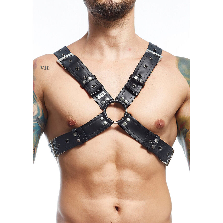 Harnais d'epaule homme en cuir a anneau central vu de trois quarts, sangles montant sur les epaules pour un look fetichiste, porte sur un buste masculin.